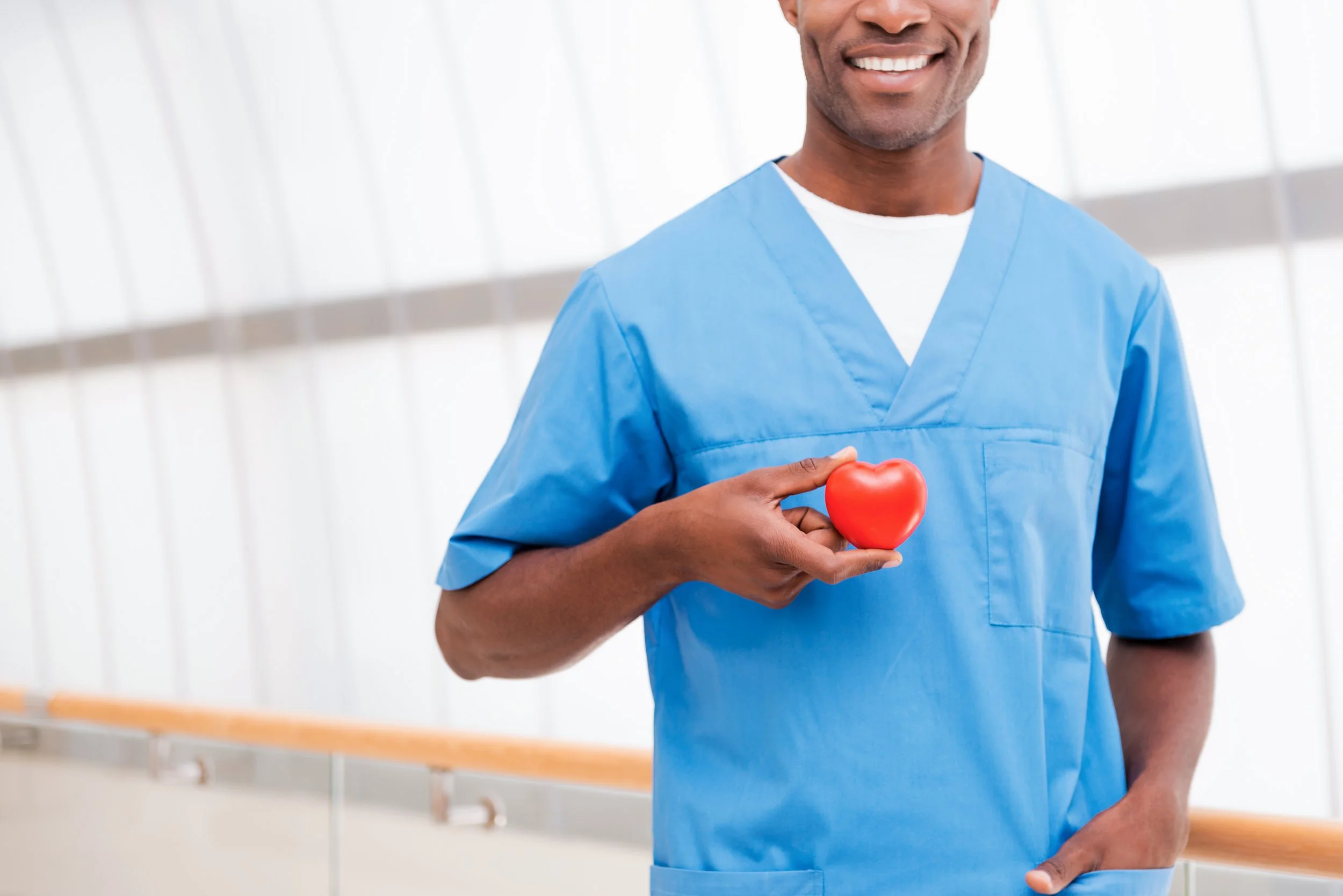 Healthcare worker in blue scrubs holding a red heart
