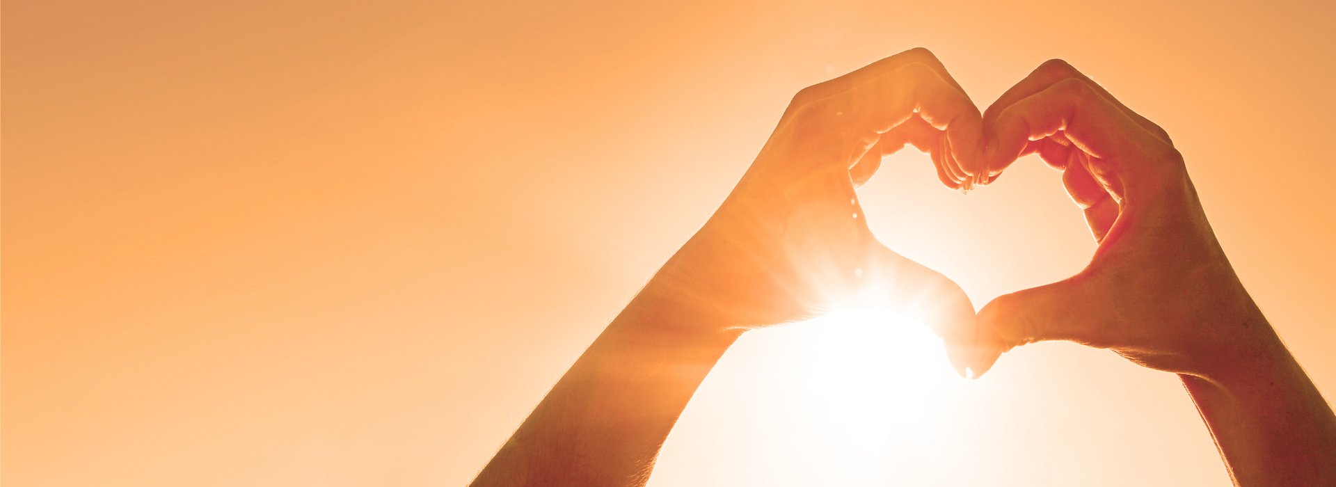 Hands making a heart shape in sunlight