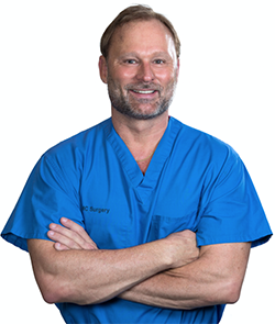 Dr. B. Dean McDaniel in blue scrubs with arms crossed