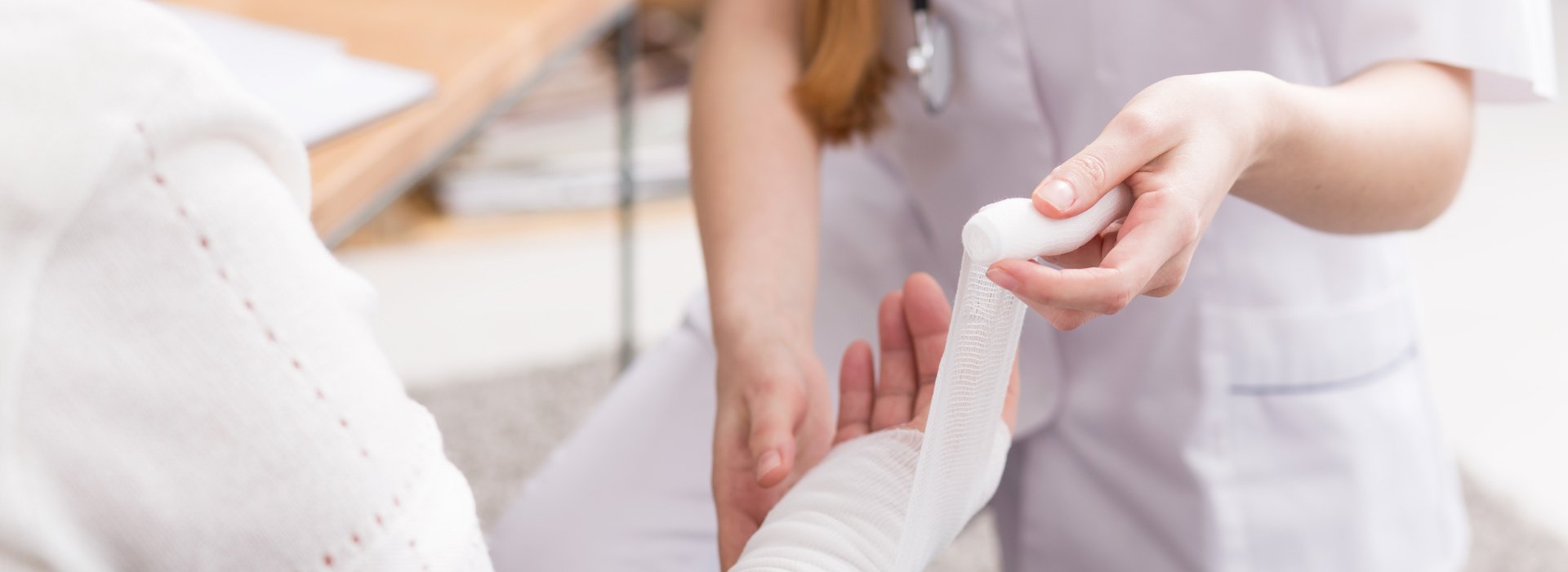 Clinician wrapping a patient&rsquo;s bandaged arm